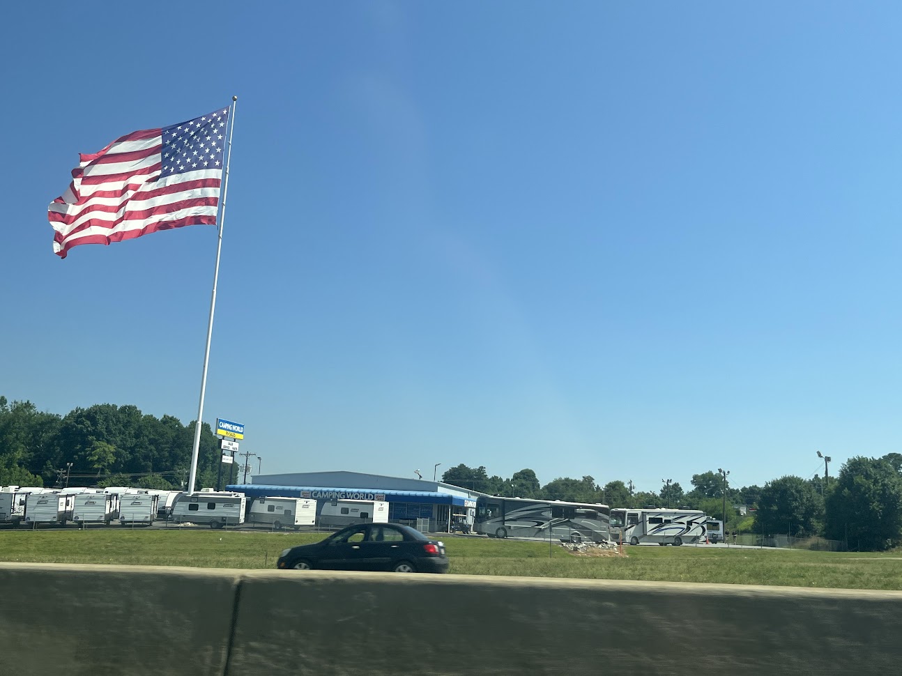 American flag flying over a camper park next to a busy highway