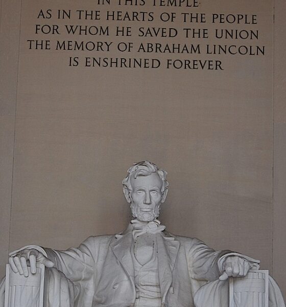 Abraham Lincoln seated in his famous chair in the Lincoln Memorial. Above him is his epitaph.