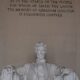 Abraham Lincoln seated in his famous chair in the Lincoln Memorial. Above him is his epitaph.