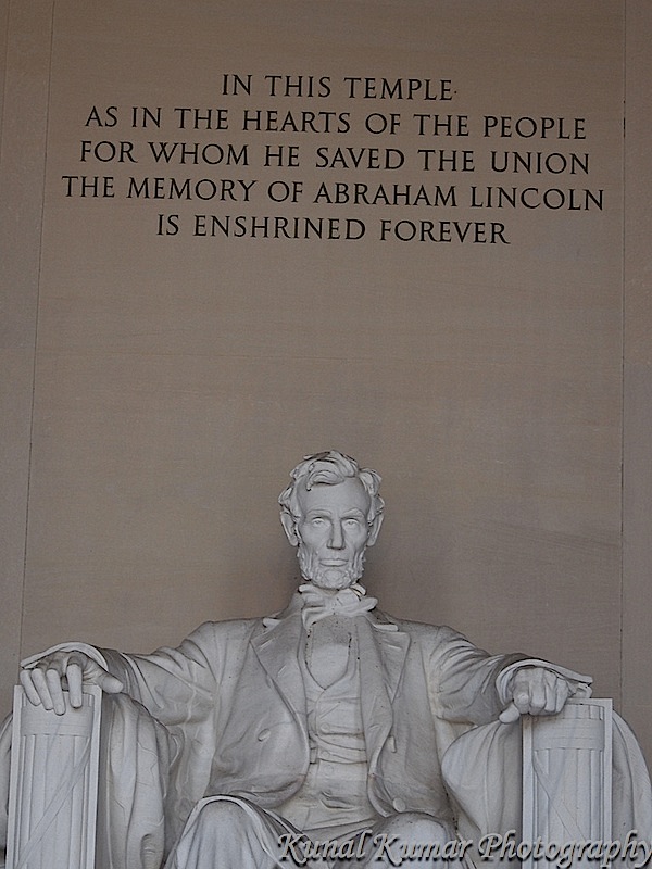 Abraham Lincoln seated in his famous chair in the Lincoln Memorial. Above him is his epitaph.