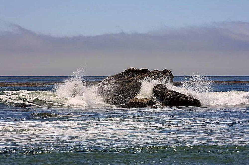 Ocean waves crashing against rocks on their way inshore.