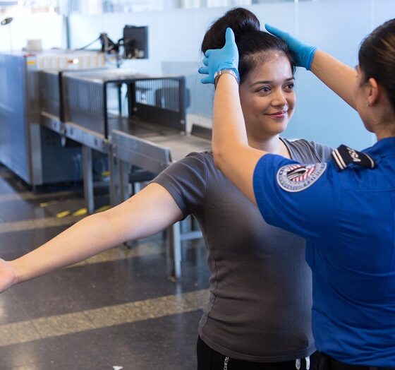 TSA officer searching an airline passenger's hair