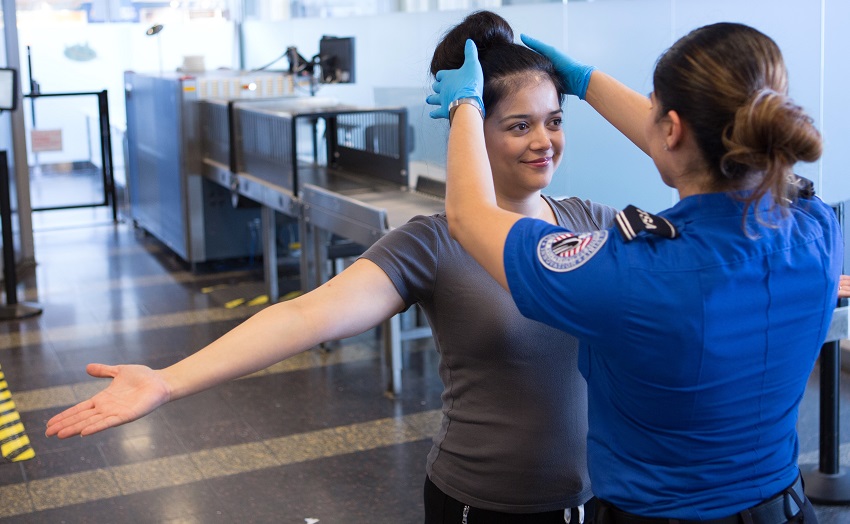 TSA officer searching an airline passenger's hair