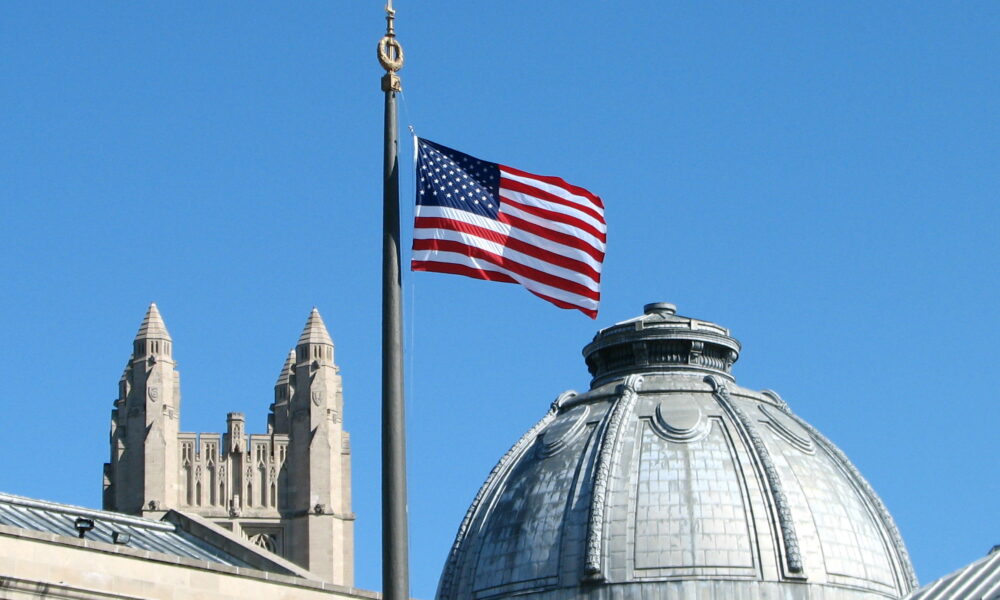 The American Flag flies from the flagpole in Hewitt Quadrangle at Yale University. Buildings shown include the Yale Commons (left foreground), the dome of Theodore Dwight Woolsey Memorial Hall (wherein are inscribed the names of every Yale graduate who ever fell in battle, including President Franklin D. Roosevelt in the WWII memorial section), and the top of Sterling Tower (background, across the intersection of College, Grove, and Prospect Streets). Note: Sheffield-Sterling-Strathcona Hall (abbreviated SSS) is the headquarters of the School of Engineering.