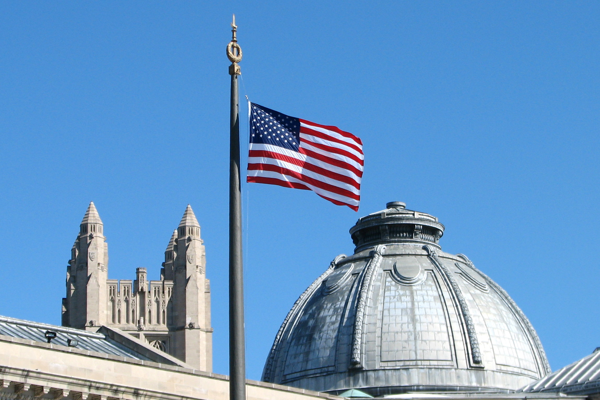 The American Flag flies from the flagpole in Hewitt Quadrangle at Yale University. Buildings shown include the Yale Commons (left foreground), the dome of Theodore Dwight Woolsey Memorial Hall (wherein are inscribed the names of every Yale graduate who ever fell in battle, including President Franklin D. Roosevelt in the WWII memorial section), and the top of Sterling Tower (background, across the intersection of College, Grove, and Prospect Streets). Note: Sheffield-Sterling-Strathcona Hall (abbreviated SSS) is the headquarters of the School of Engineering.
