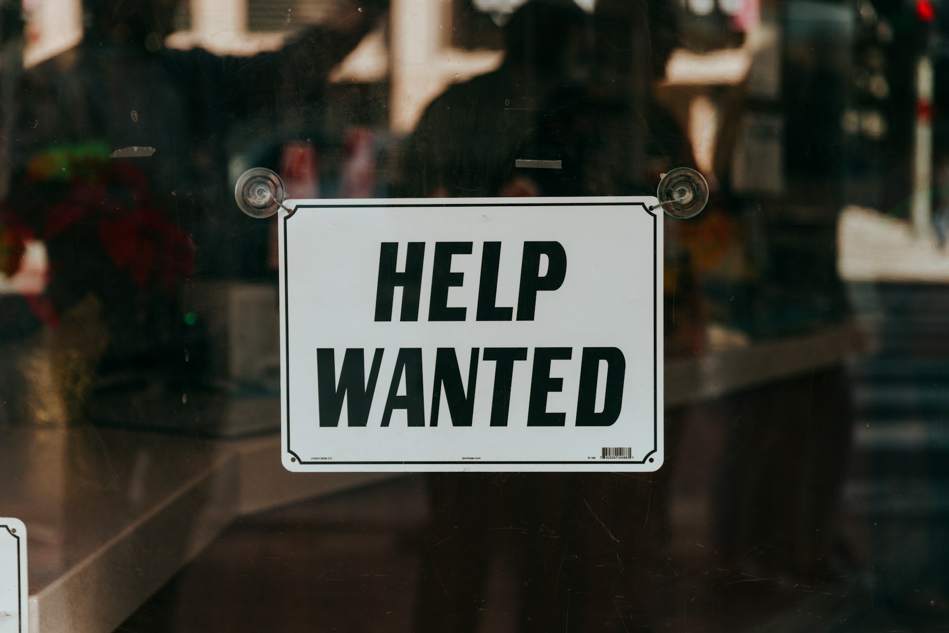 Help Wanted sign outside a retail bar or store - by Nathan Dumlao on Unsplash