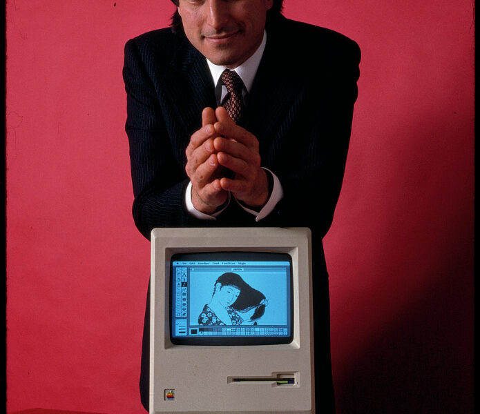 Steve Jobs, founder of Apple Computer, shown with his most famous invention, the first Apple Macintosh