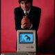 Steve Jobs, founder of Apple Computer, shown with his most famous invention, the first Apple Macintosh
