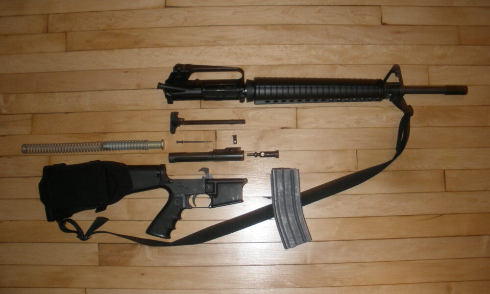 An Armalite AR-15 stripped down, showing receiver, clip, firing pin, barrel, etc.