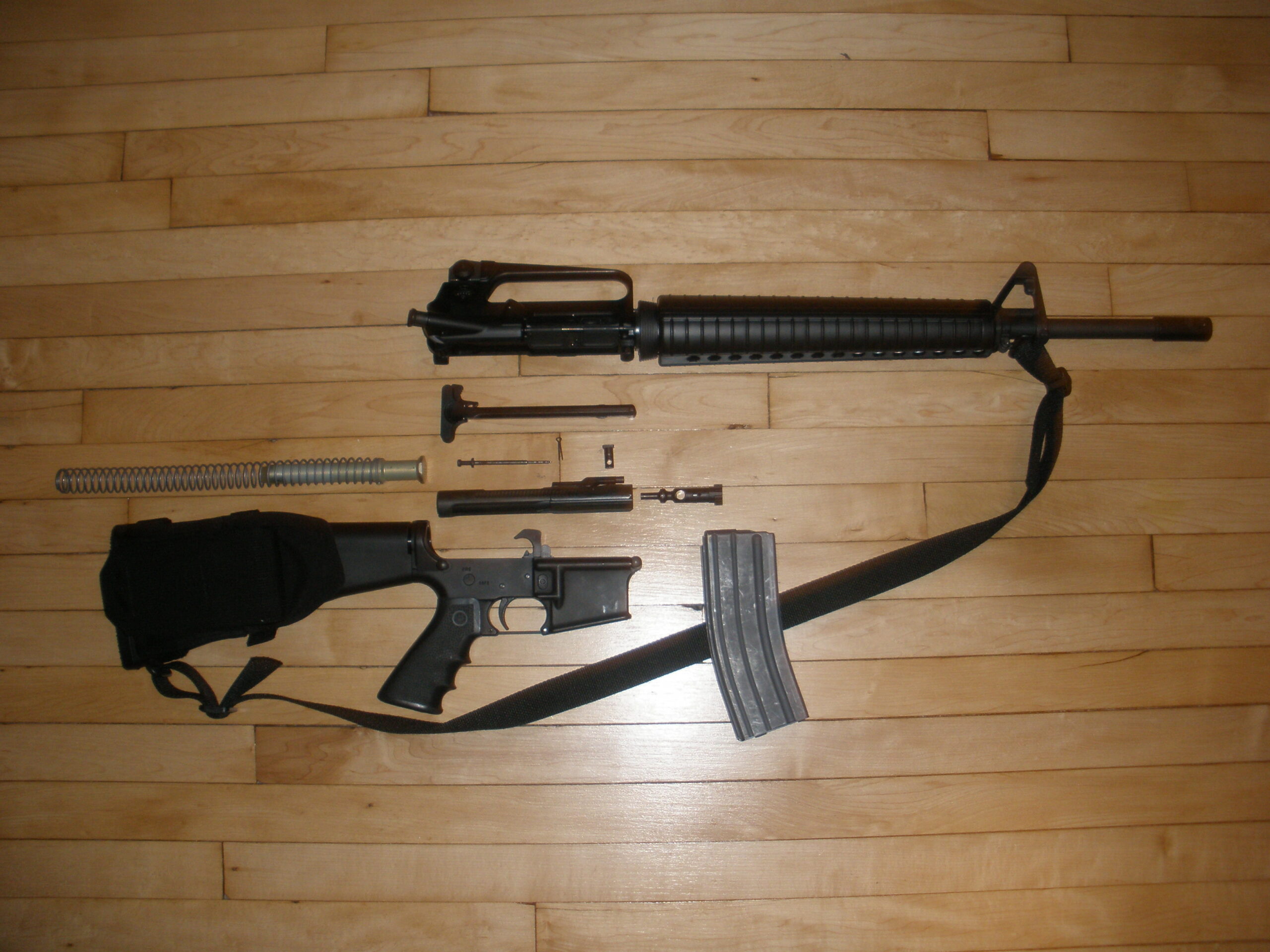 An Armalite AR-15 stripped down, showing receiver, clip, firing pin, barrel, etc.