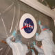 Workers apply a NASA logo to a payload