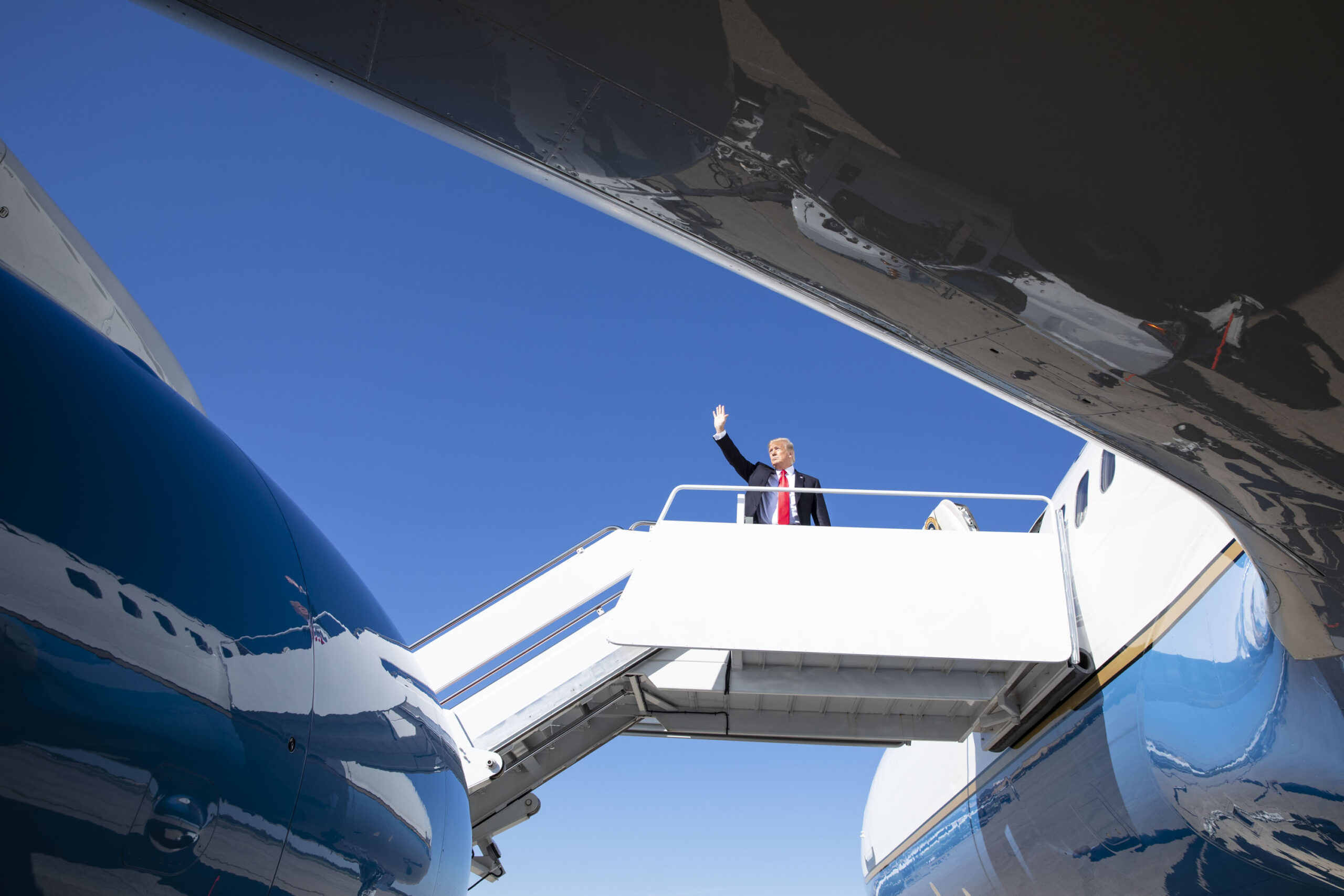 President Trump at the top of the boarding ramp leading into one of his Air Force One planes